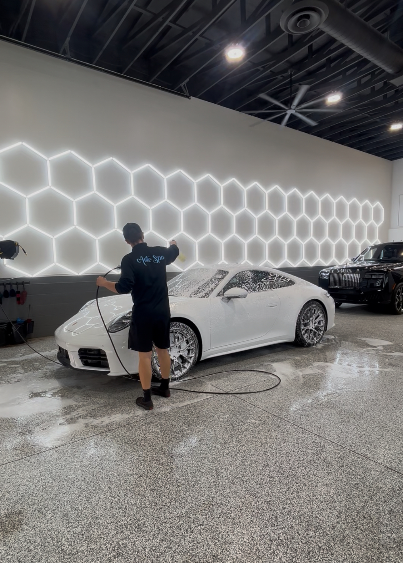The Auto Spa professional detailing shop interior with hexagonal lighting and Porsche being detailed